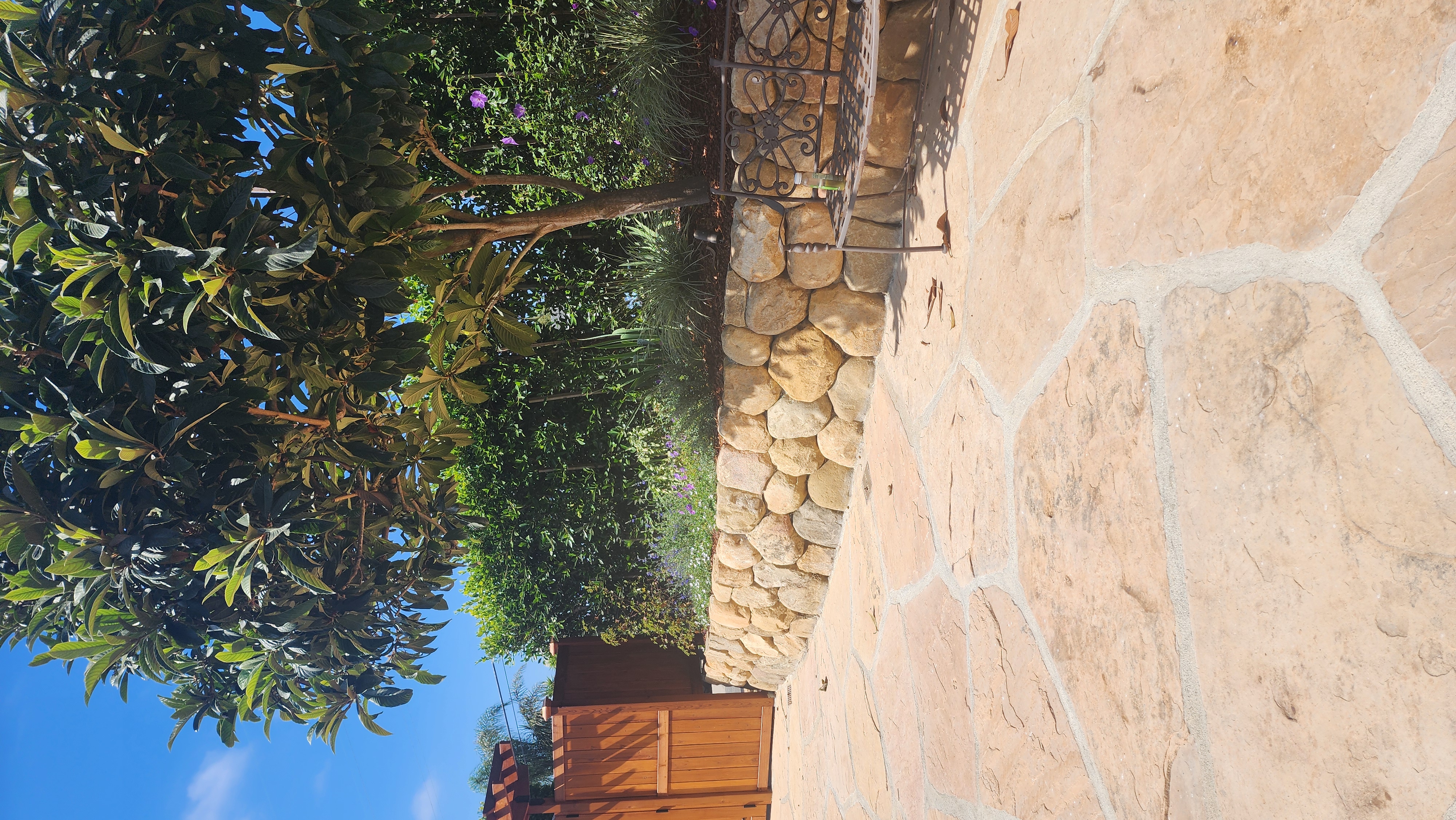 Natural flagstone patio with curved boulder retaining wall in a Santa Barbara hillside garden.