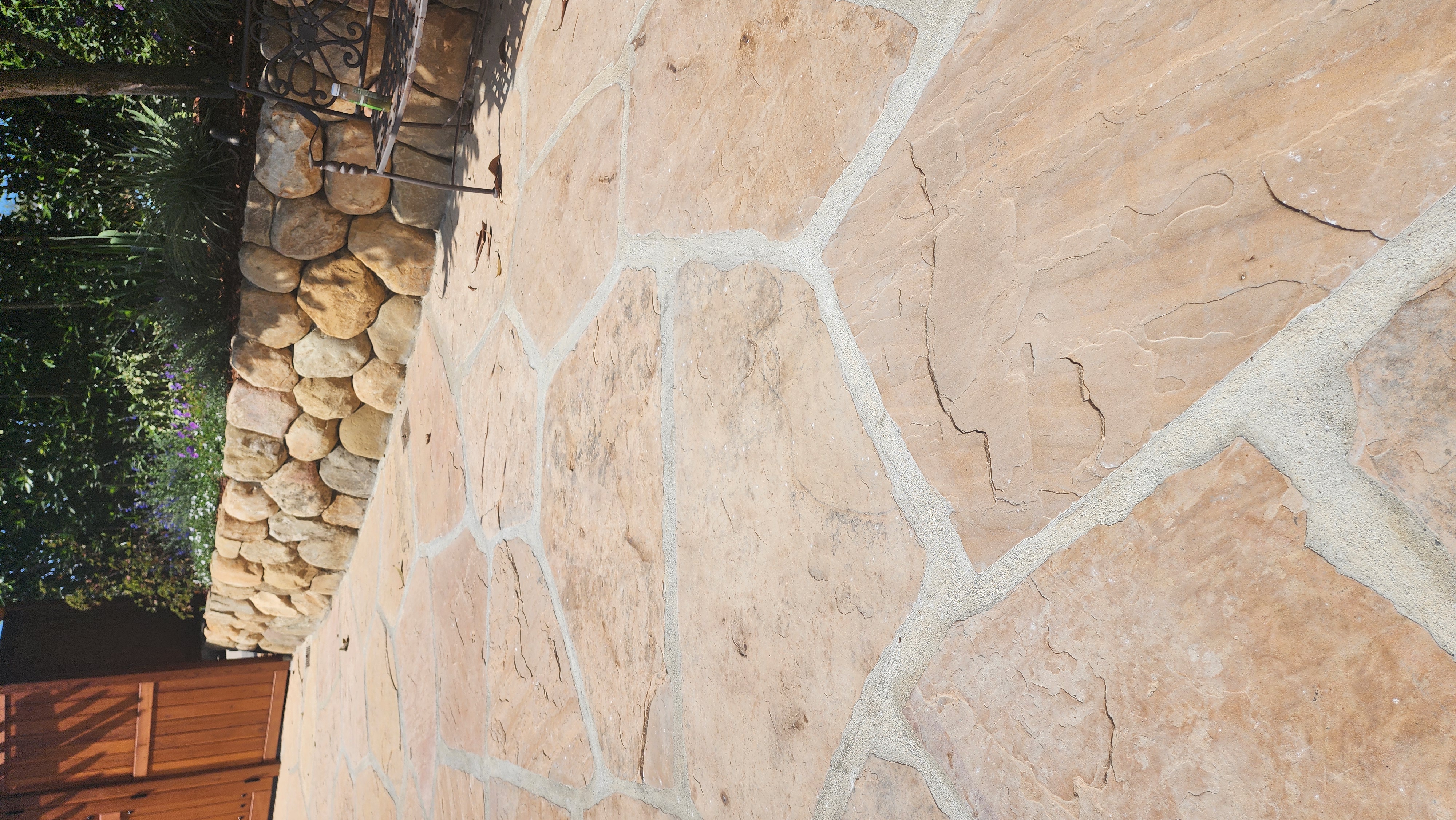 Sun-drenched flagstone patio bordered by a natural stone retaining wall and lavender plantings.