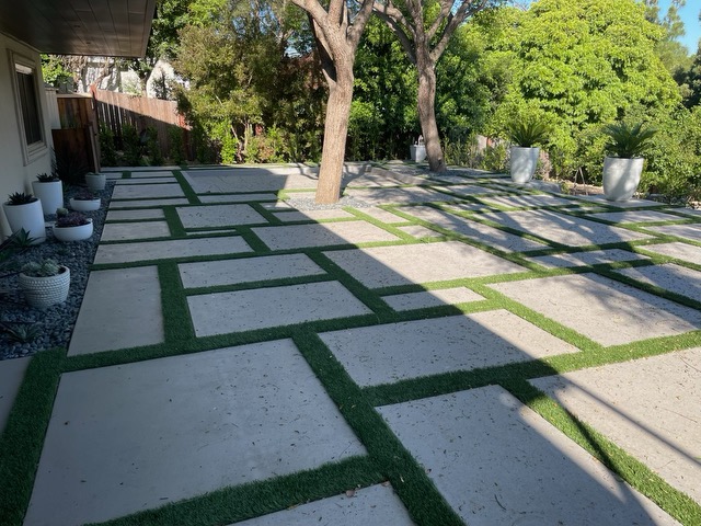 Contemporary concrete paver patio with turf strips and succulent planters in Santa Barbara.