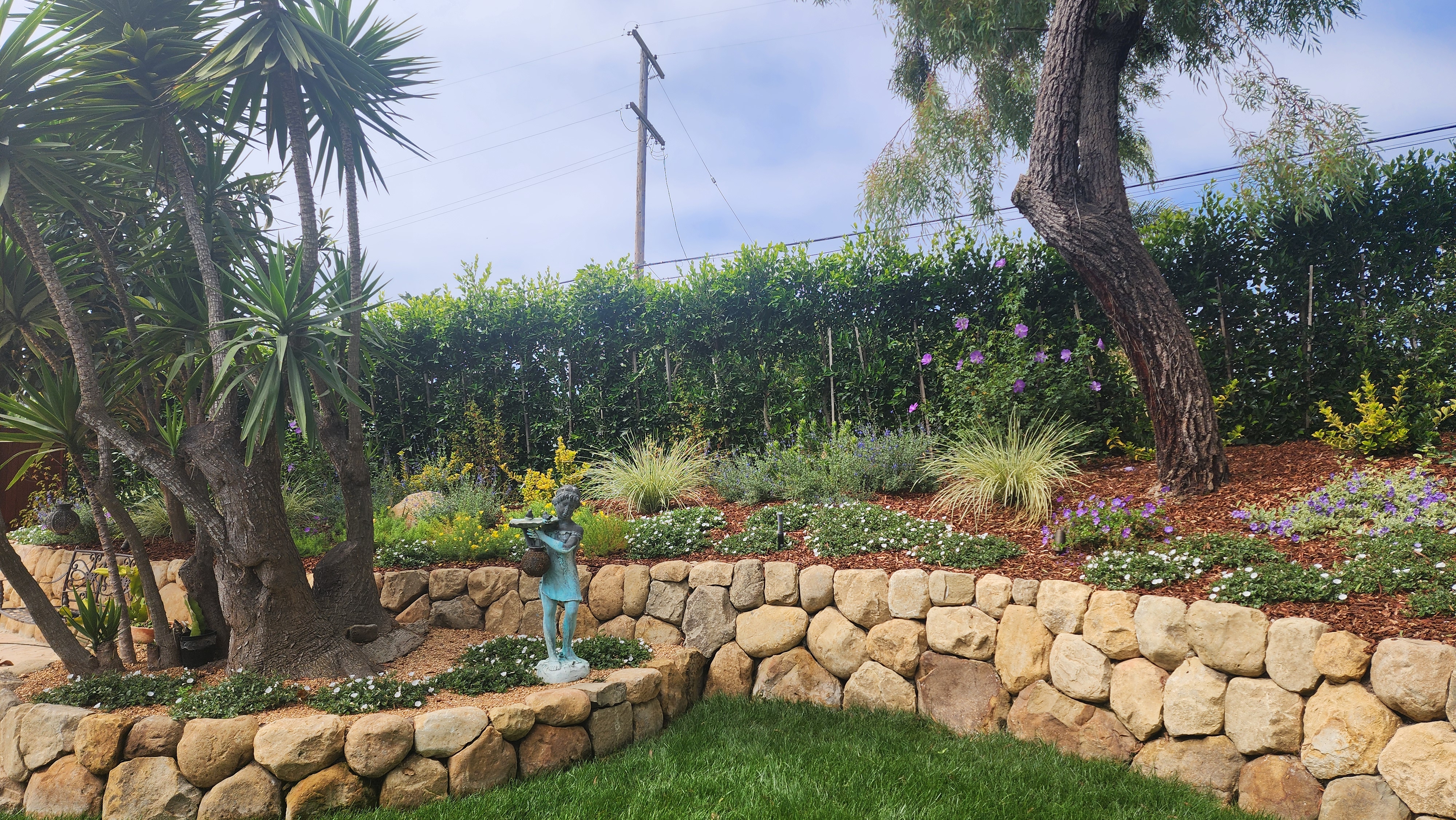 Two-tier natural stone retaining wall with tropical plantings in a Santa Barbara backyard.