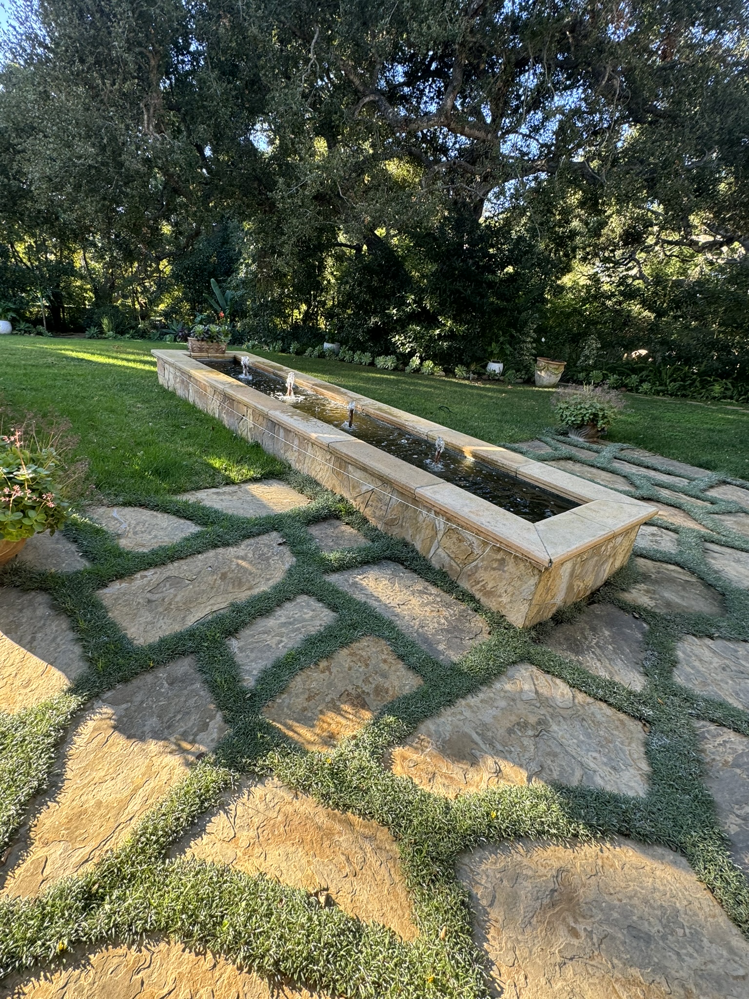 Custom natural stone water feature with bubbling jets on a flagstone patio in Santa Barbara.