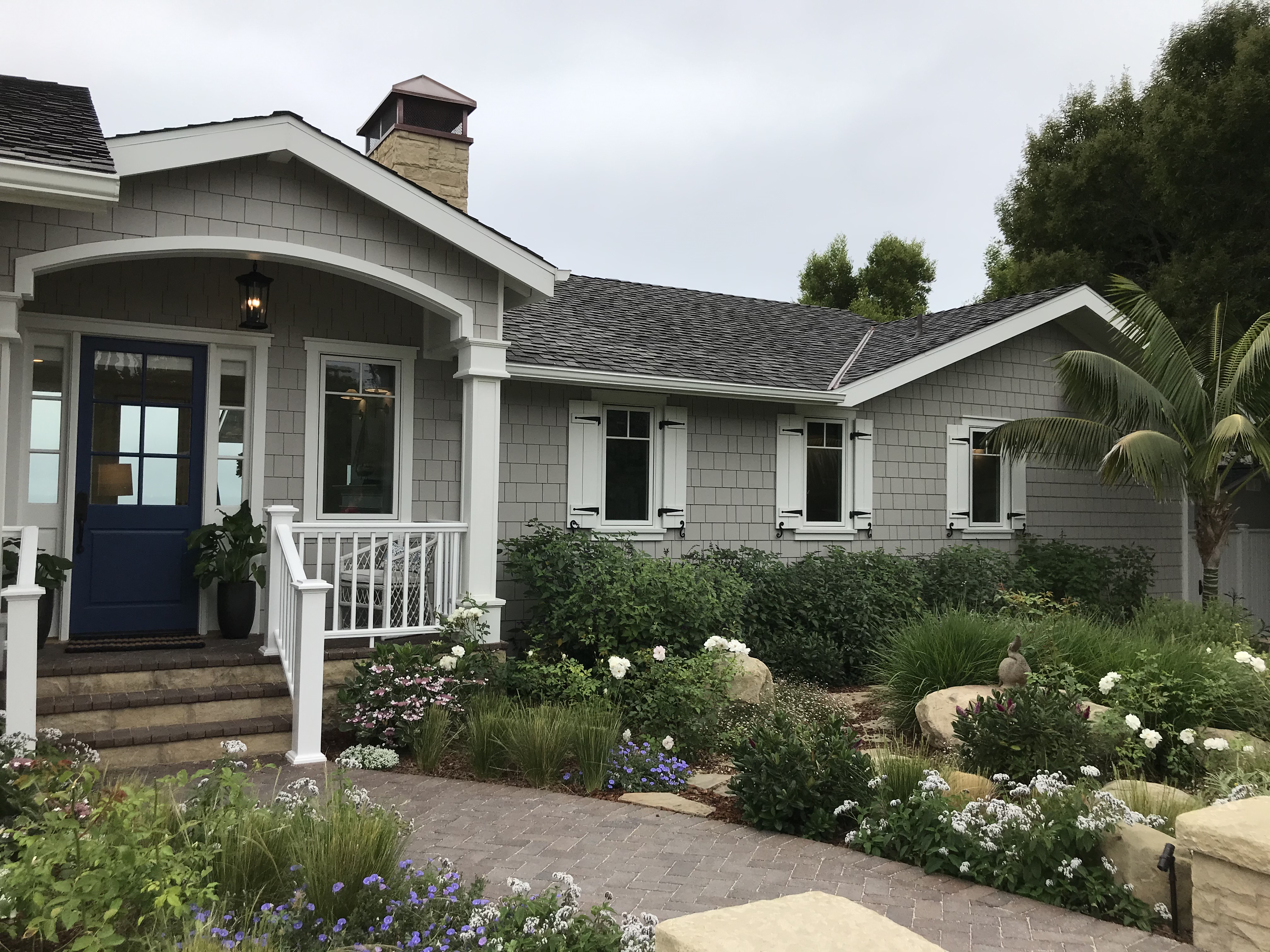 Lush English-style front garden with roses and paver walkway at a Santa Barbara estate.