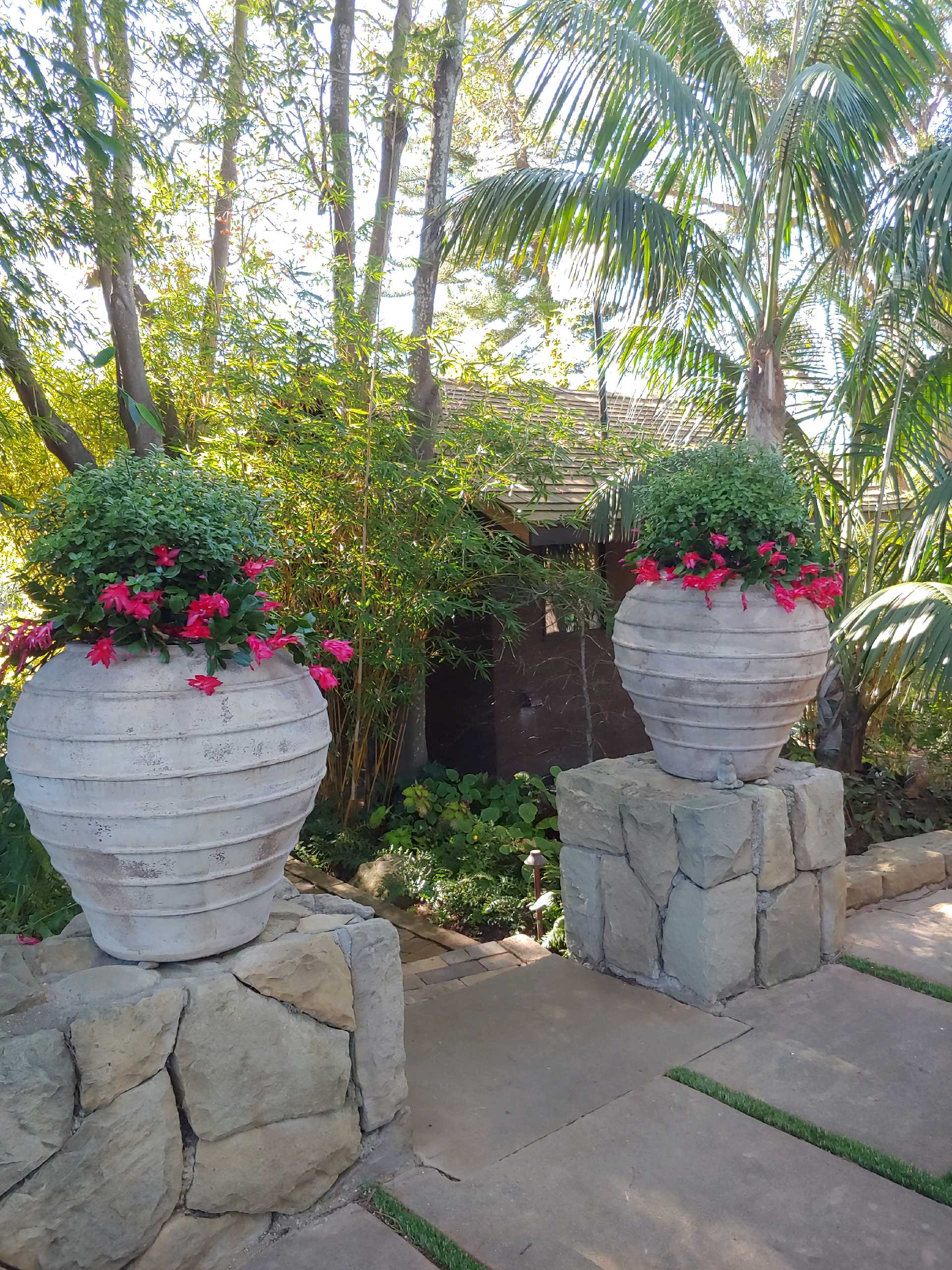 Tropical garden entrance with stone pillars, palms, and bamboo in Santa Barbara.