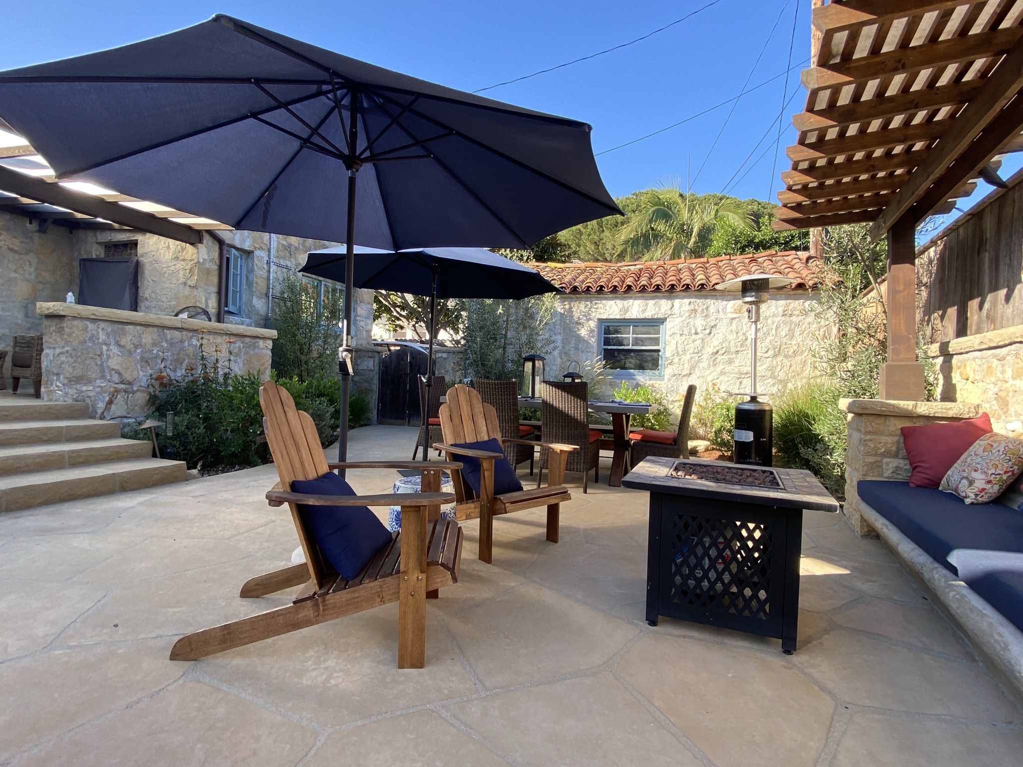 Mediterranean-style flagstone patio with fire pit lounge seating in Santa Barbara.