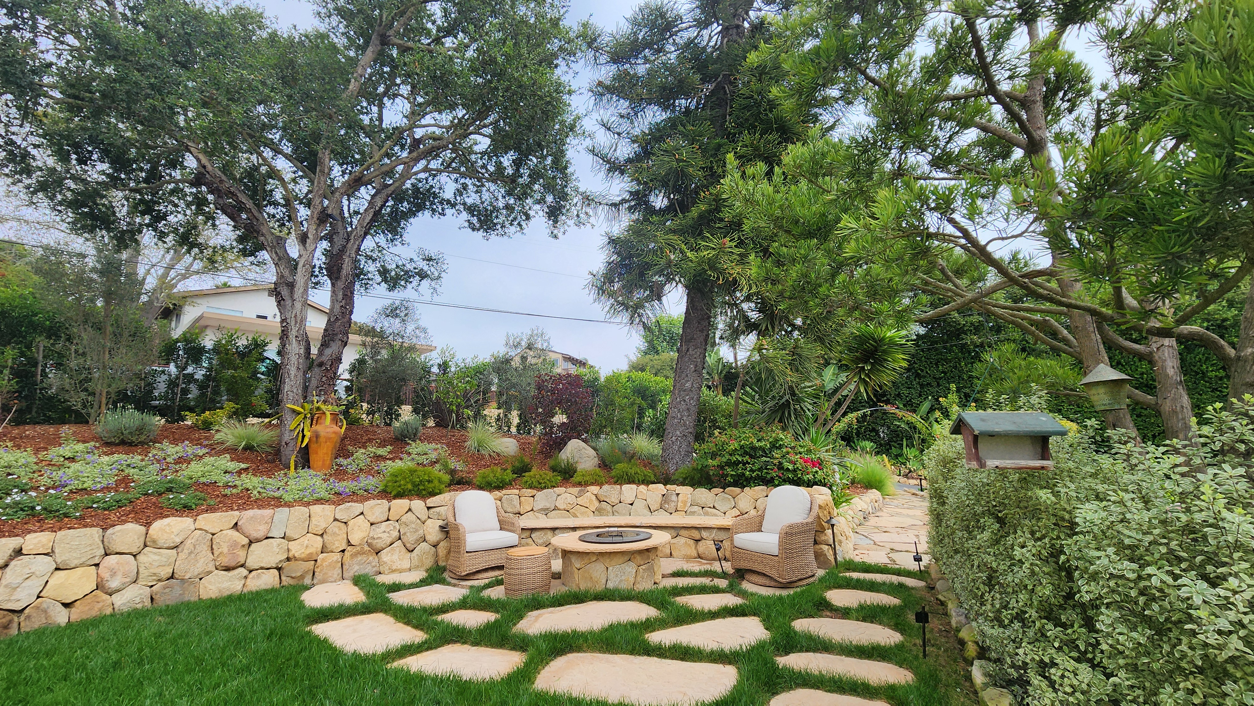 Cozy stone fire pit seating area with flagstone path in a Santa Barbara garden.