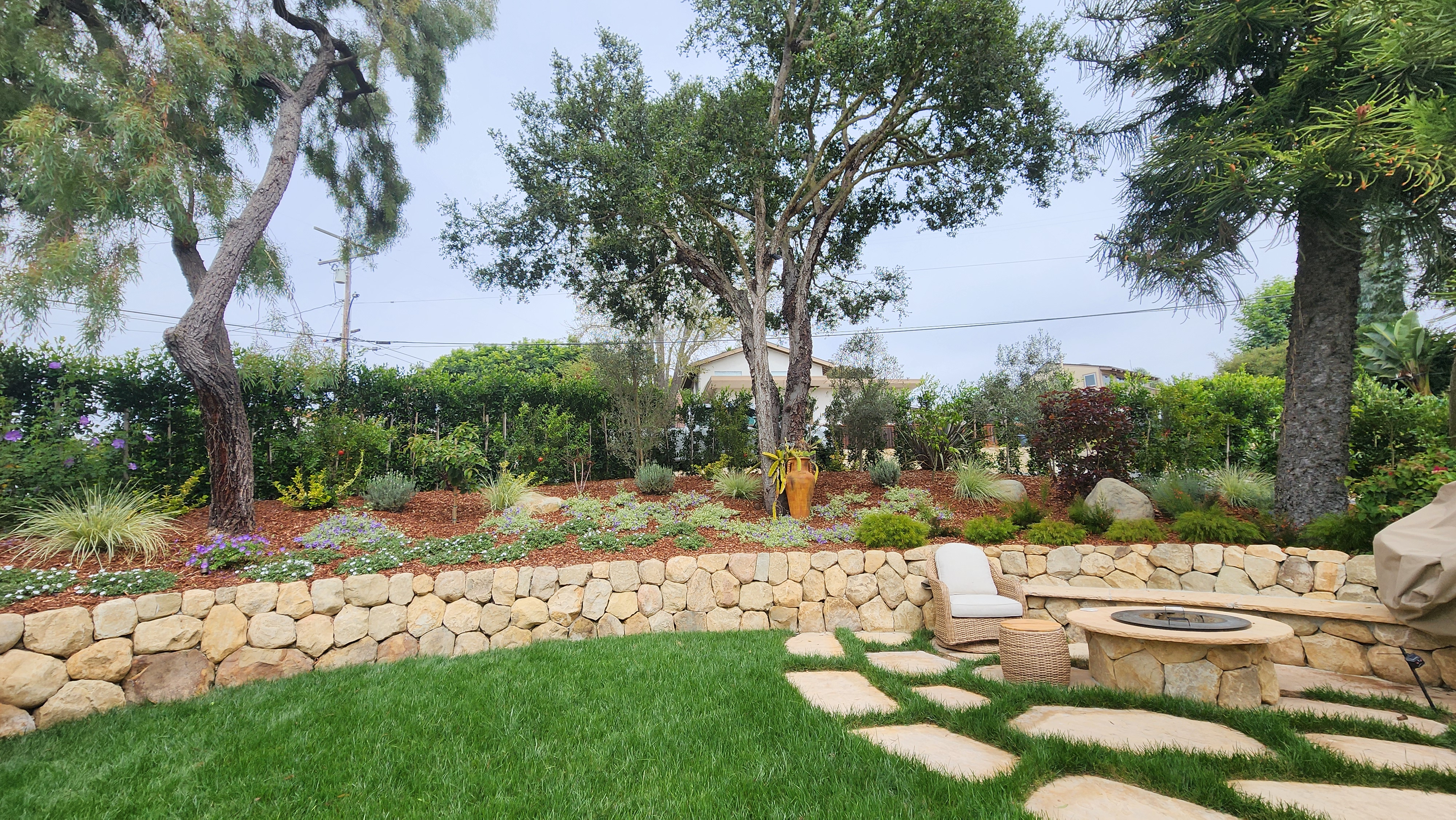 Natural stone fire pit with flagstone patio and retaining wall in a Santa Barbara backyard.