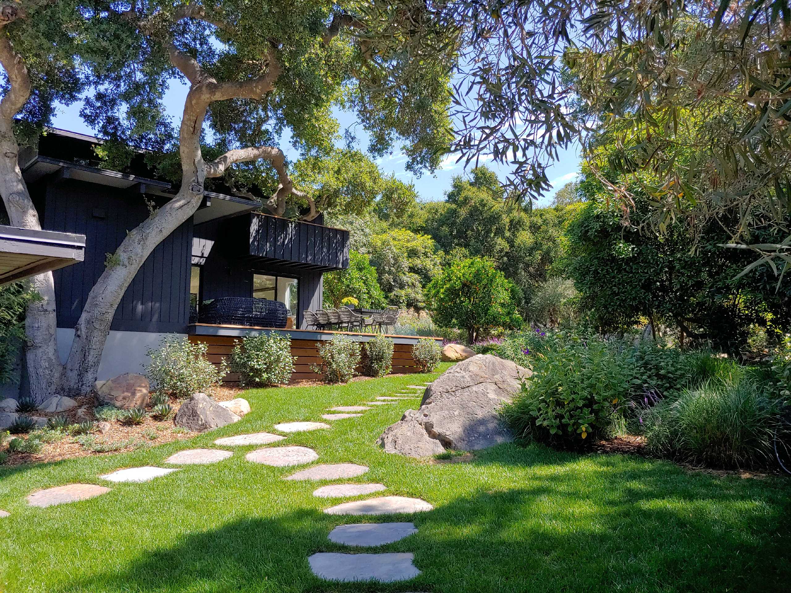 Outdoor dining deck with flagstone path through an oak-shaded Santa Barbara backyard.